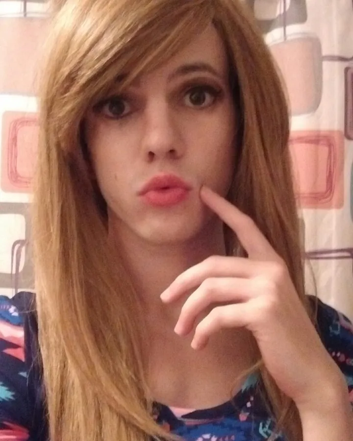 Jeune femme trans européenne aux cheveux blonds, posant de face, avec un pénis artificiel visible sous un slip blanc, regardant l'objectif